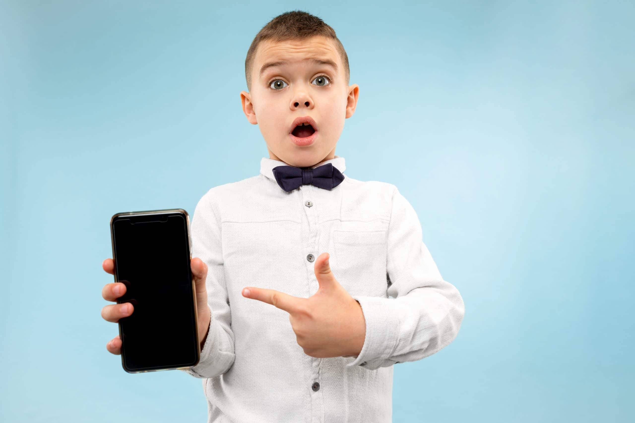 Indoor portrait of attractive young boy holding blank smartphone actividades para hacer con niños ver películas